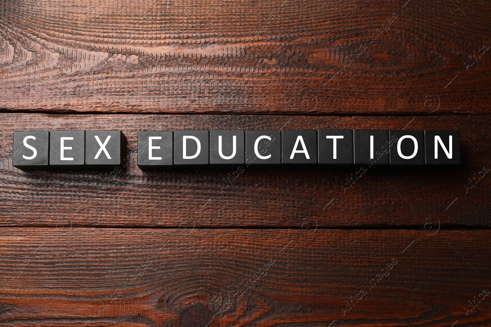 Photo of Phrase Sex Education made with cubes on wooden table, top view