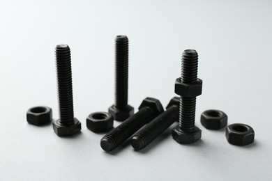 Photo of Metal bolts and nuts on white background, closeup. Hardware tool