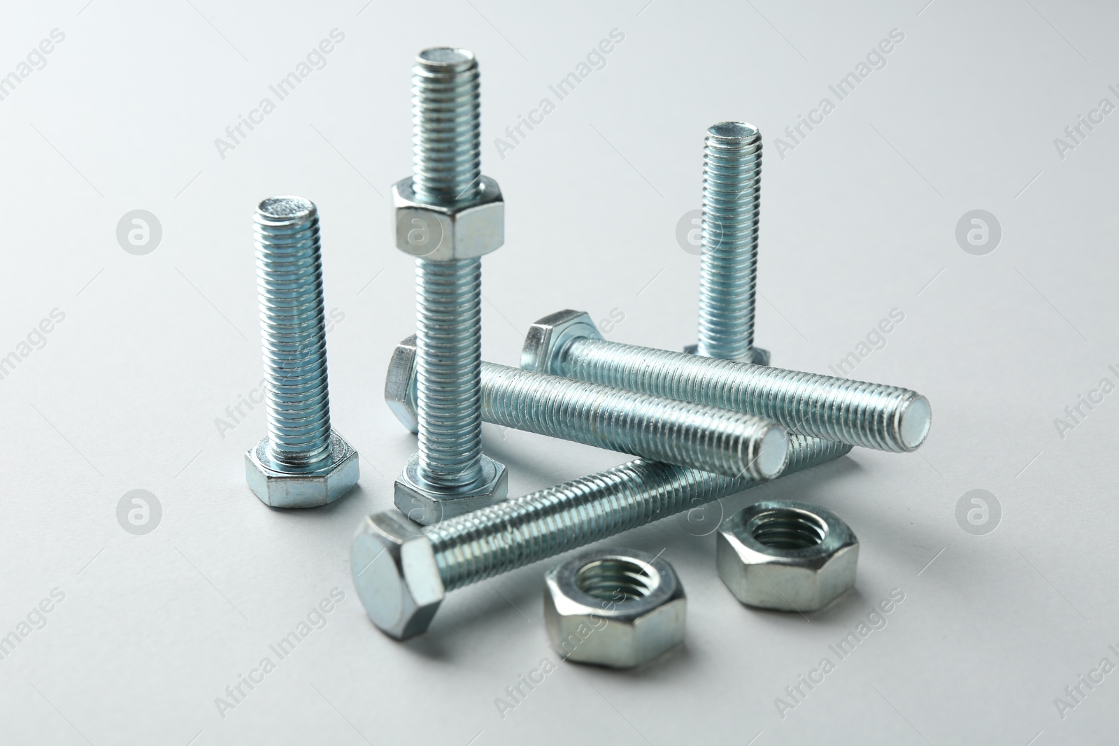 Metal bolts and nuts on white background, closeup. Hardware tool Photo of Metal bolts and nuts on white background, closeup. Hardware tool