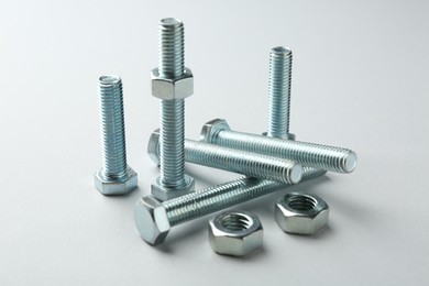 Photo of Metal bolts and nuts on white background, closeup. Hardware tool