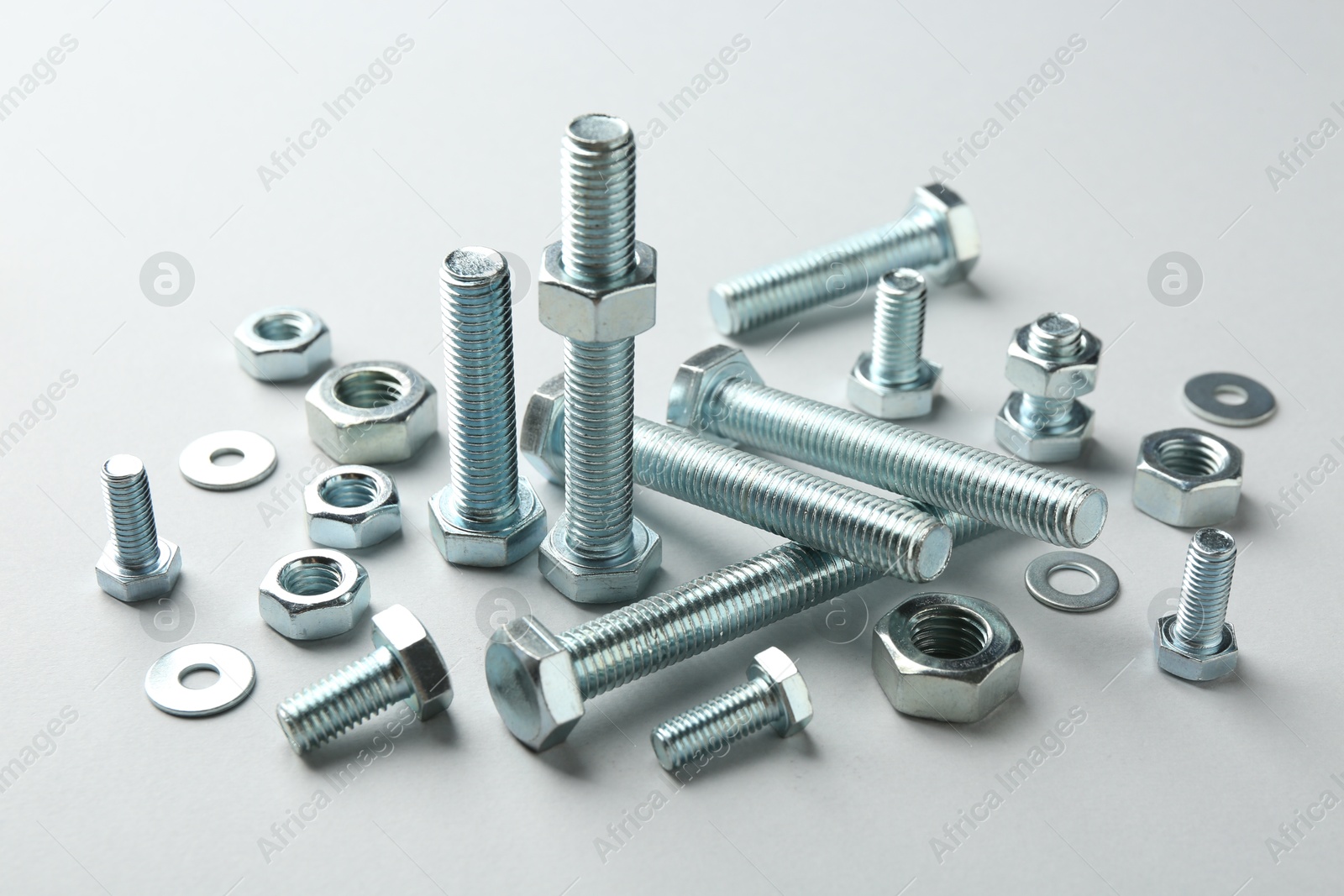 Metal bolts and nuts on white background, closeup. Hardware tool Photo of Metal bolts and nuts on white background, closeup. Hardware tool