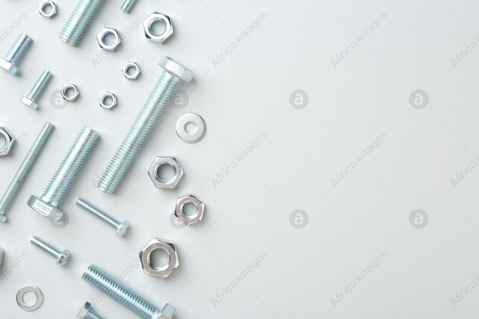 Metal bolts and nuts on white background, flat lay. Space for text Photo of Metal bolts and nuts on white background, flat lay. Space for text