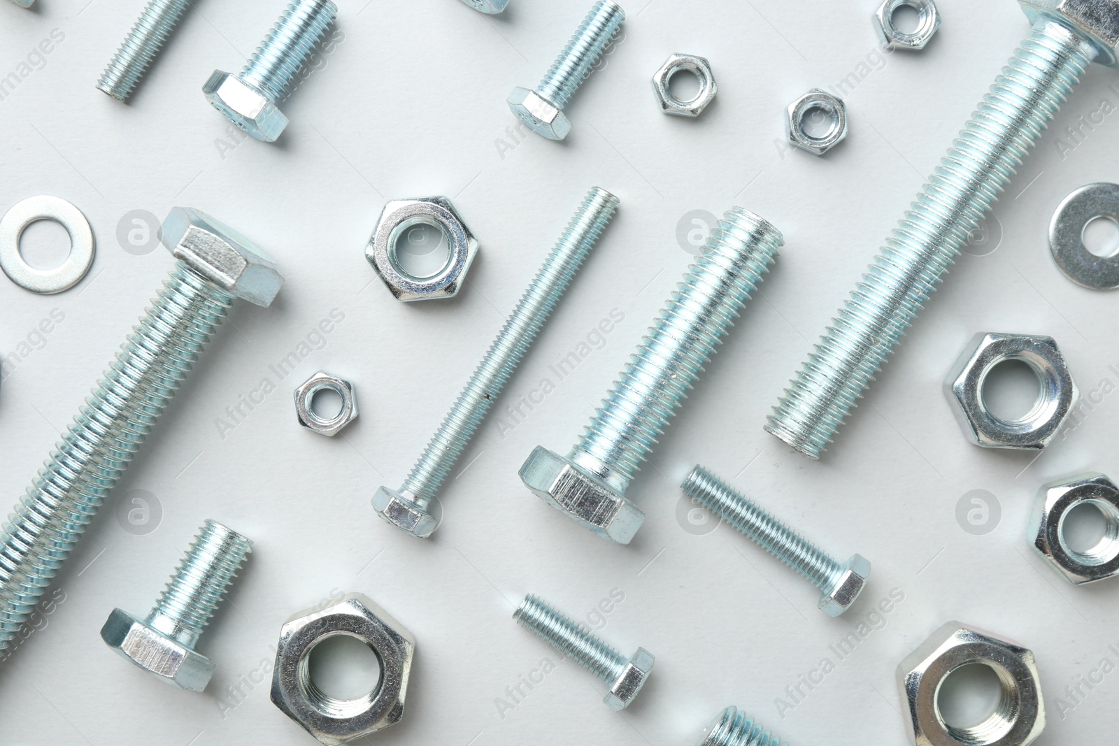 Metal bolts and nuts on white background, flat lay Photo of Metal bolts and nuts on white background, flat lay