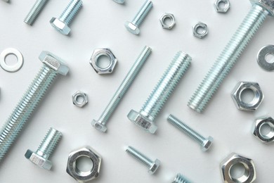 Photo of Metal bolts and nuts on white background, flat lay