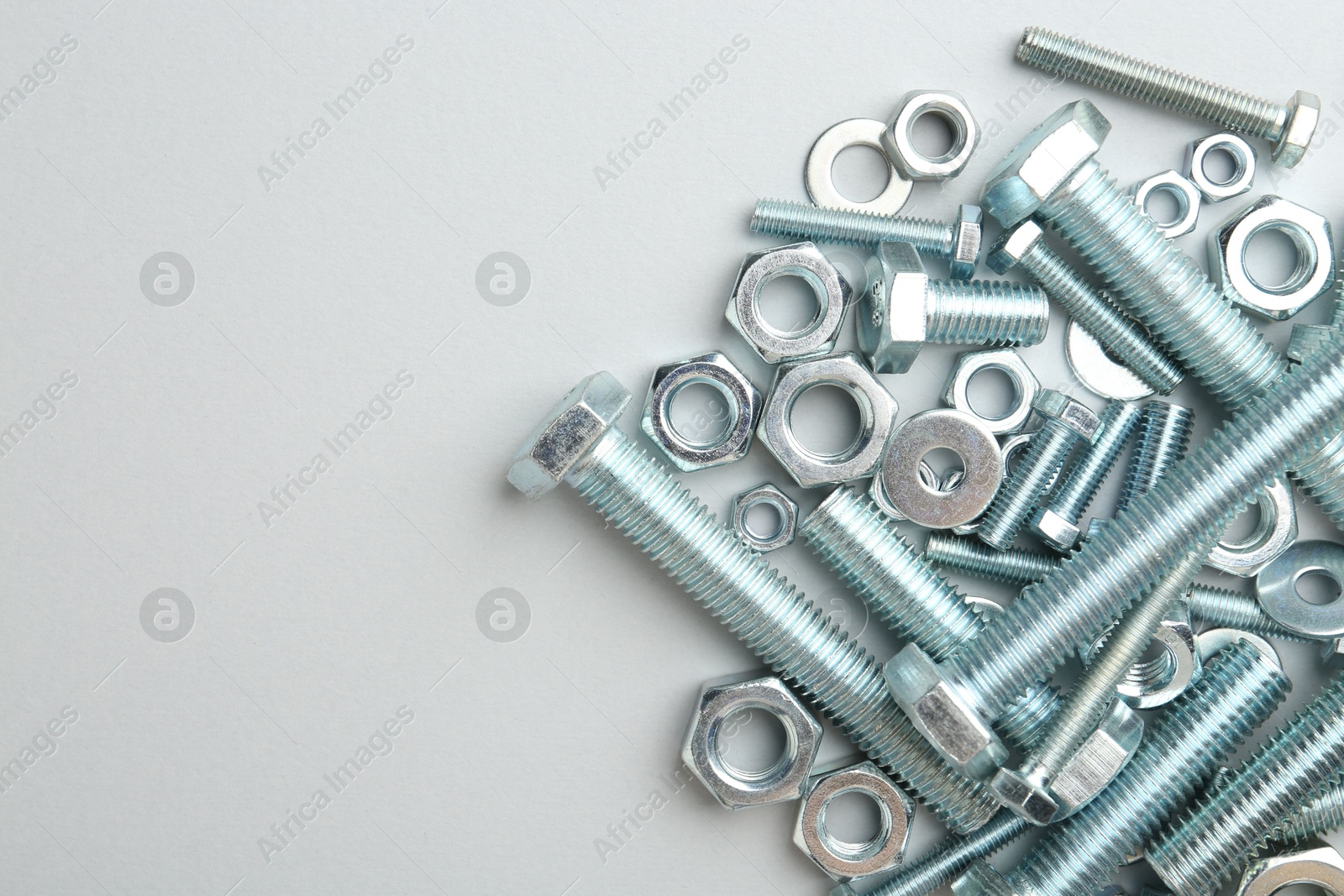 Metal bolts and nuts on white background, flat lay. Space for text Photo of Metal bolts and nuts on white background, flat lay. Space for text