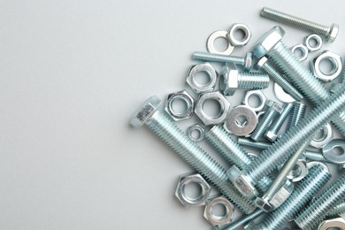 Photo of Metal bolts and nuts on white background, flat lay. Space for text