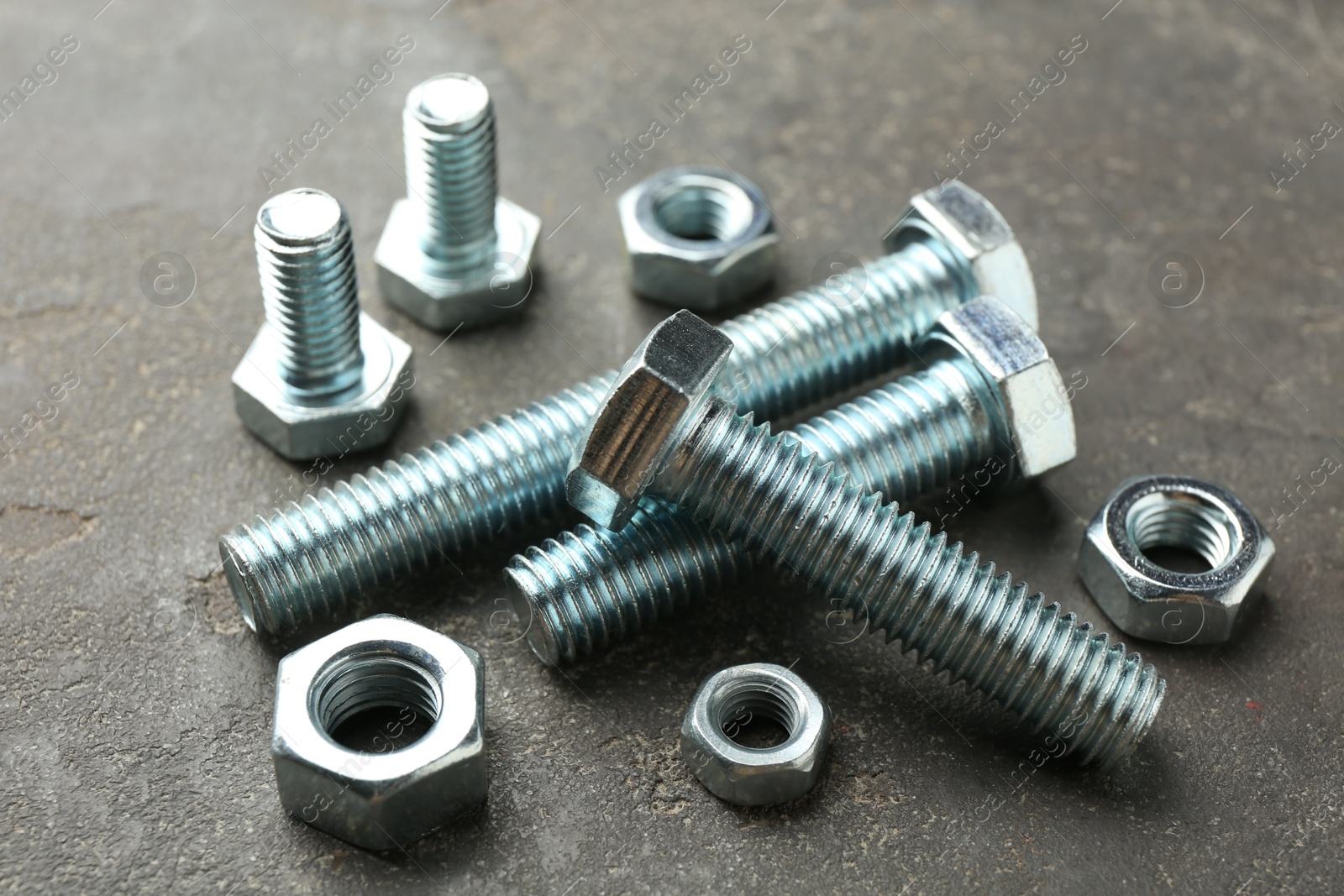 Metal bolts and nuts on grey table, closeup Photo of Metal bolts and nuts on grey table, closeup