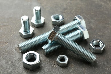 Photo of Metal bolts and nuts on grey table, closeup