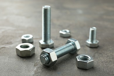 Photo of Metal bolts and nuts on grey table, closeup