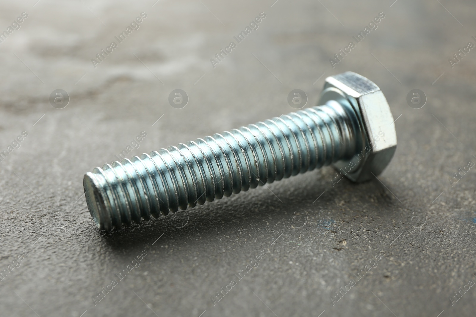 One metal bolt on grey table, closeup Photo of One metal bolt on grey table, closeup