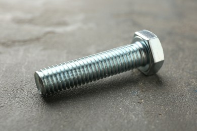 Photo of One metal bolt on grey table, closeup