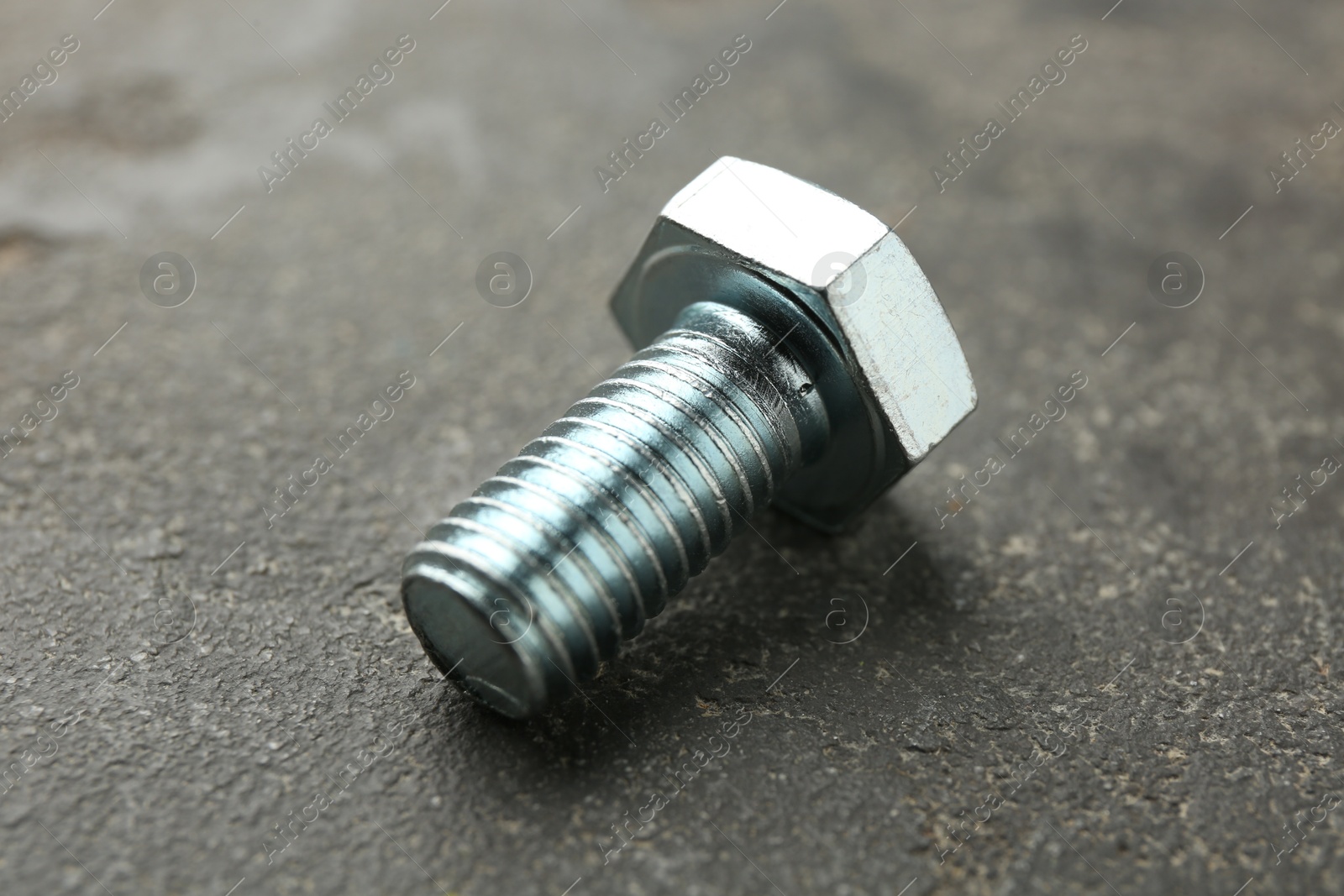 One metal bolt on grey table, closeup Photo of One metal bolt on grey table, closeup