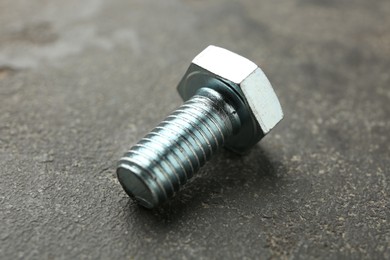 Photo of One metal bolt on grey table, closeup
