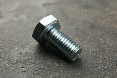 Photo of One metal bolt on grey table, closeup