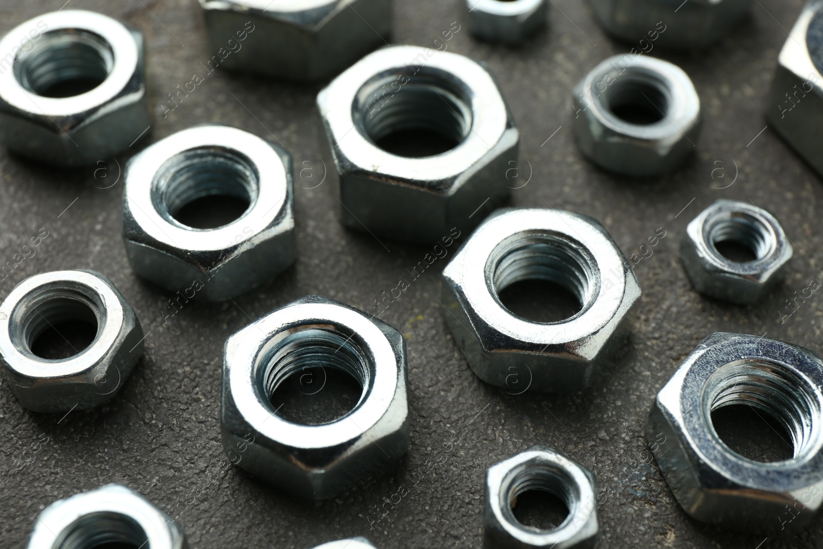Metal hex nuts on grey table, closeup Photo of Metal hex nuts on grey table, closeup