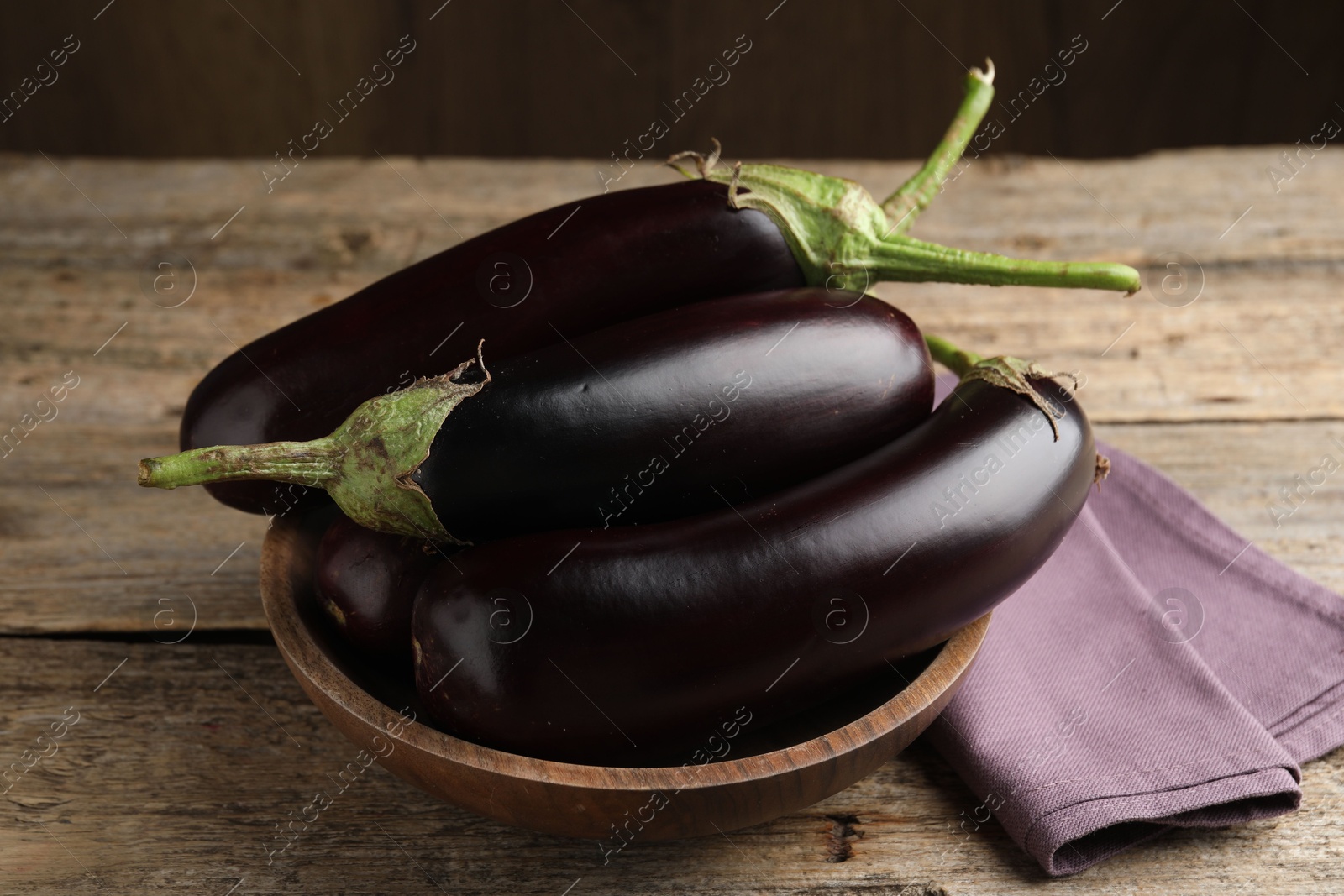 Photo of Many ripe eggplants on wooden table, closeup