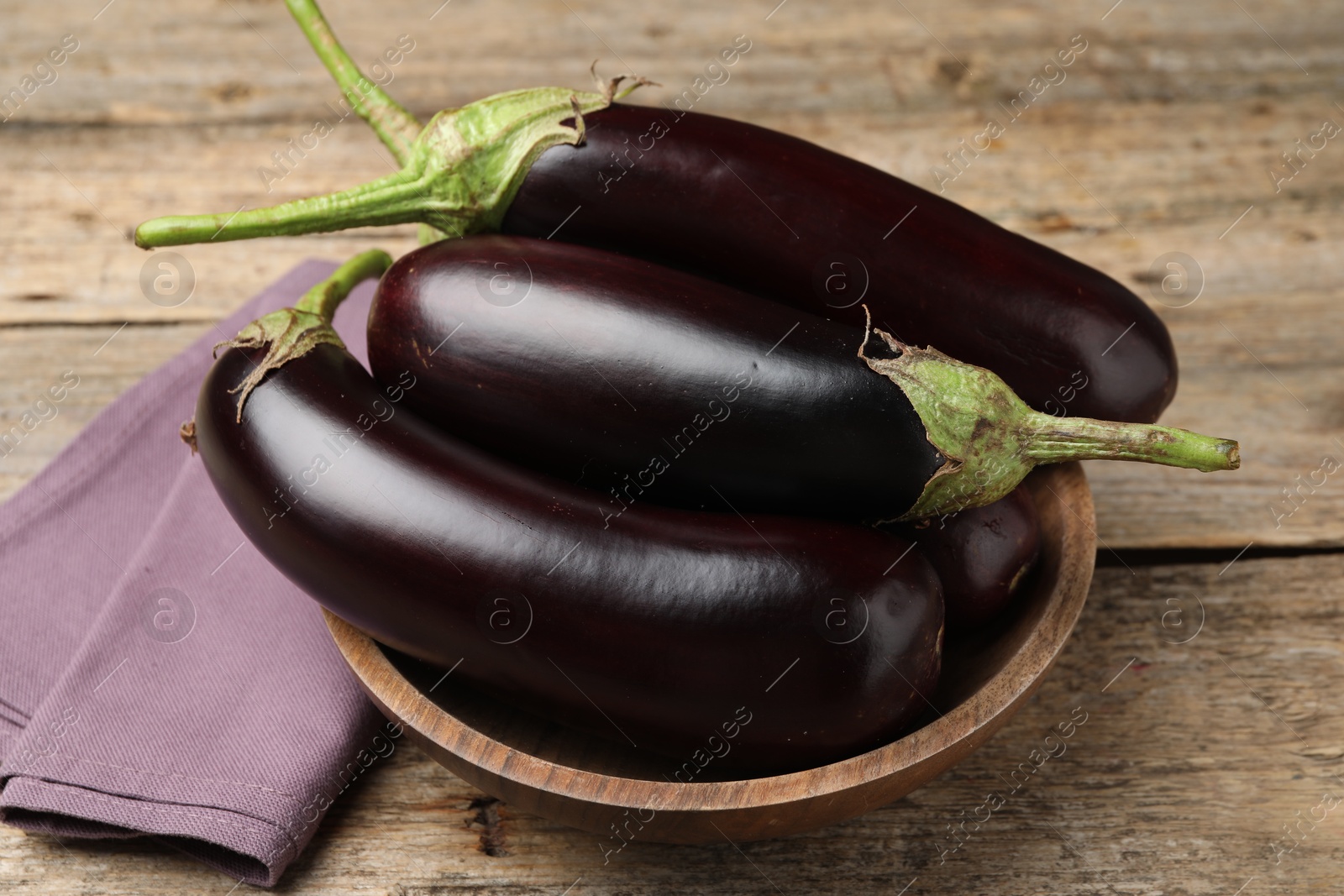 Photo of Many ripe eggplants on wooden table, closeup