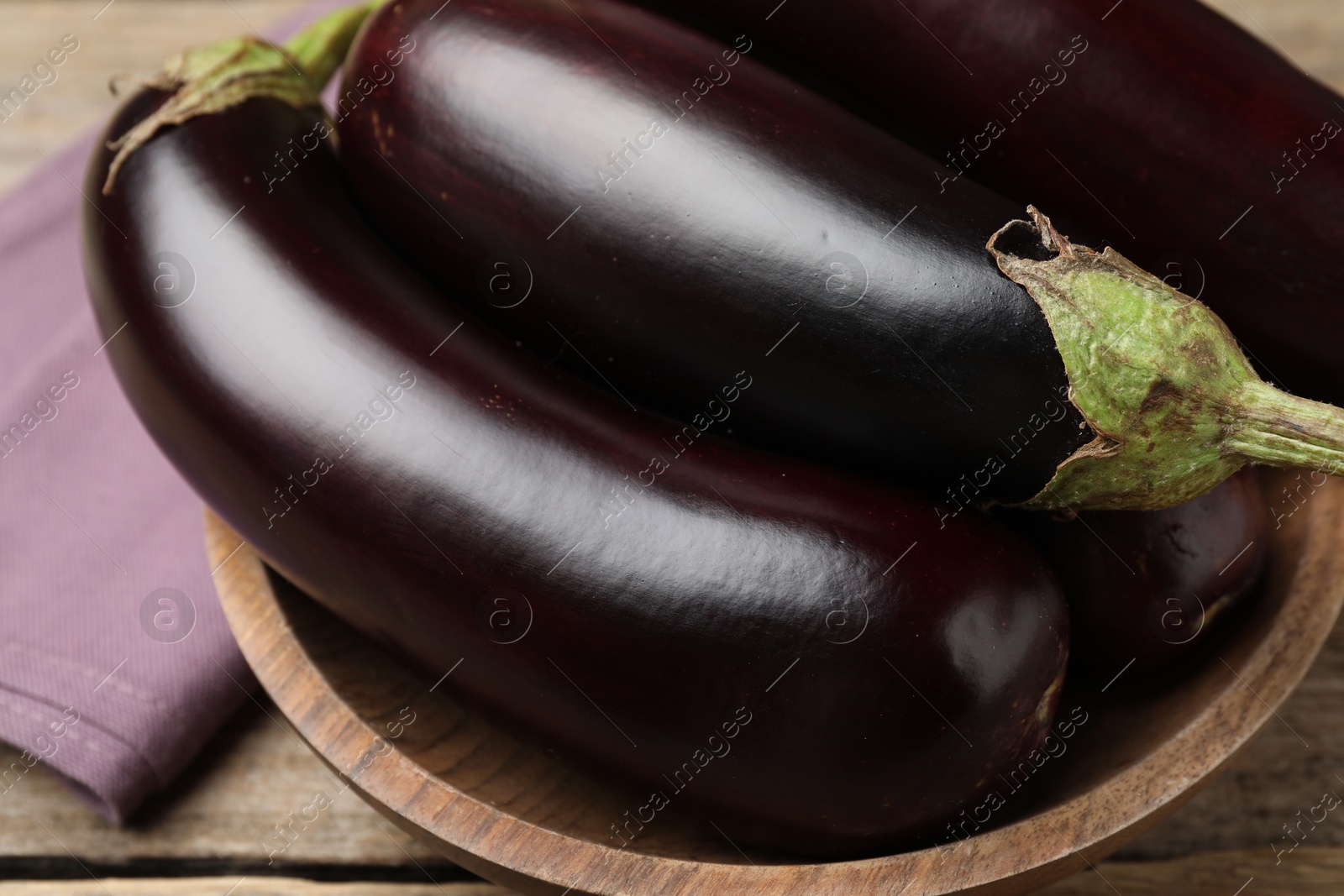 Photo of Many ripe eggplants on wooden table, closeup