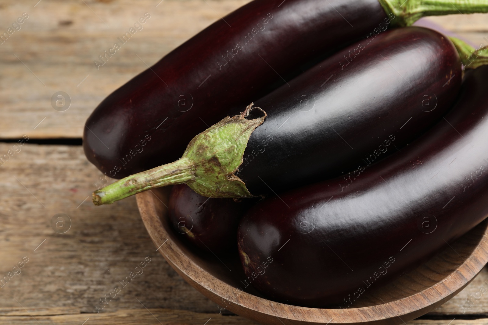 Photo of Many ripe eggplants on wooden table, closeup