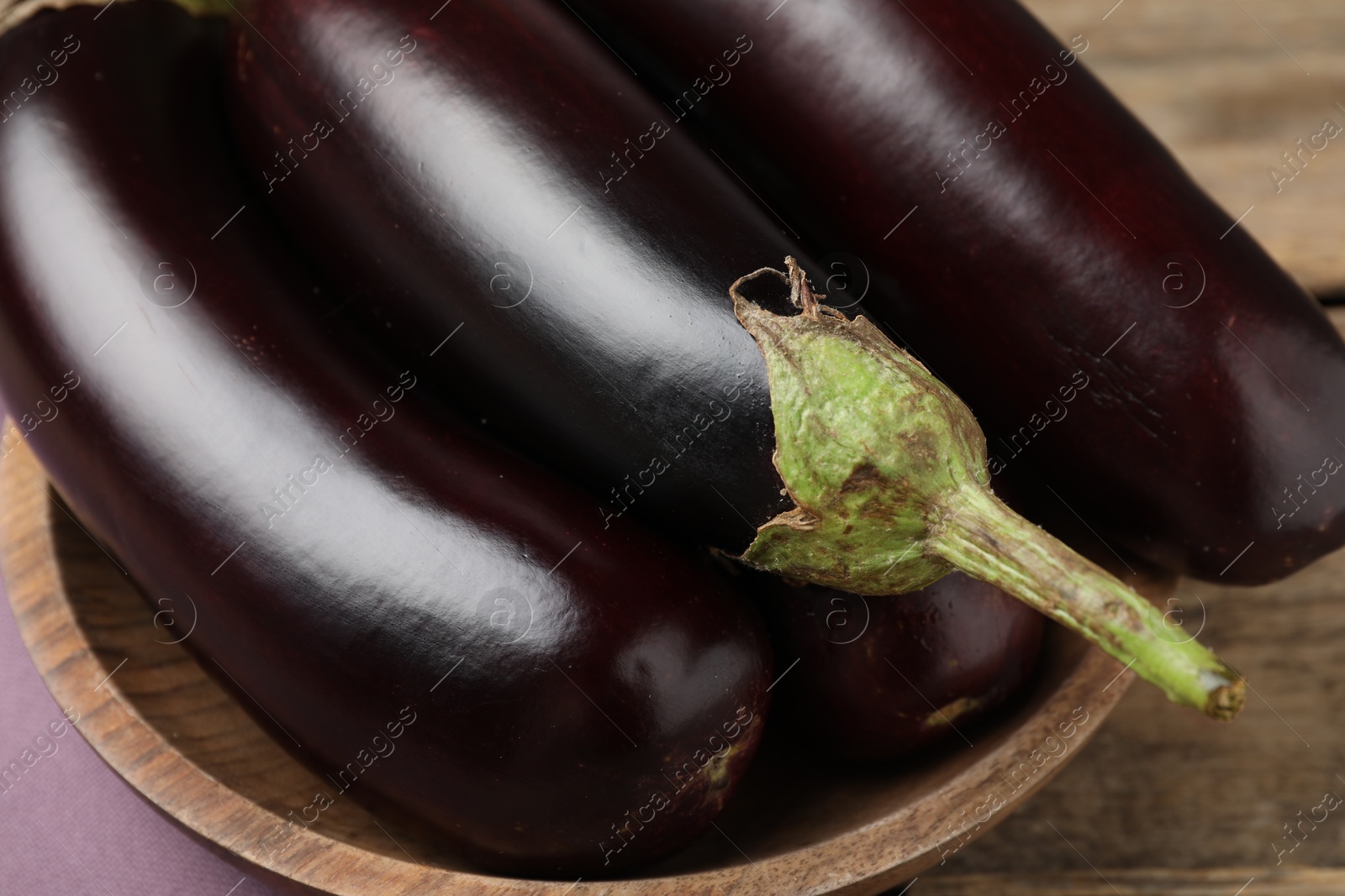 Photo of Many ripe eggplants on wooden table, closeup