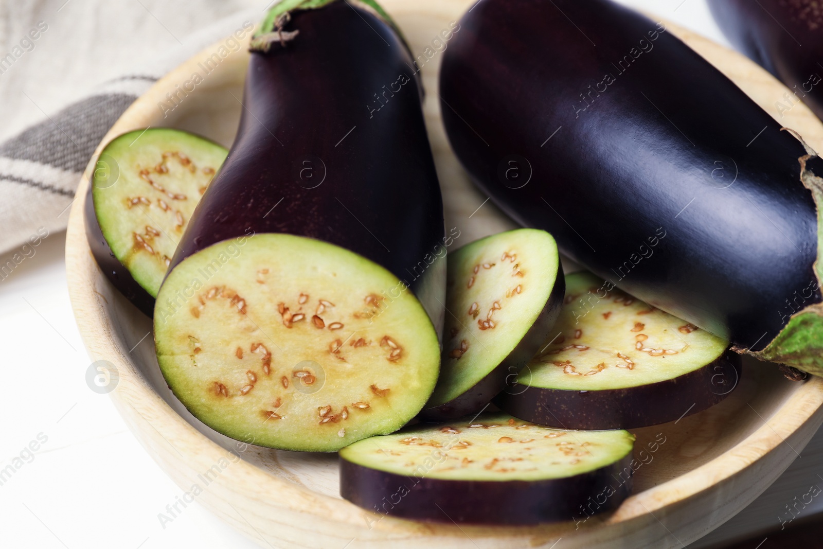 Photo of Whole and cut eggplants on white table, closeup