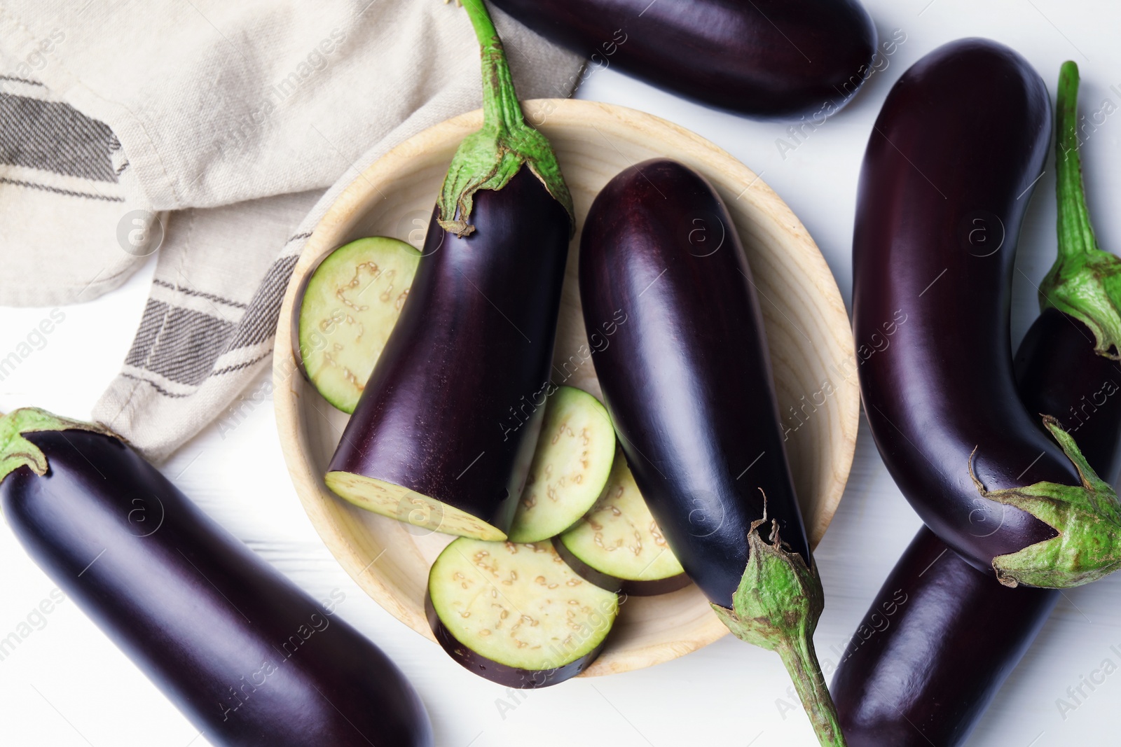 Photo of Whole and cut eggplants on white table, flat lay