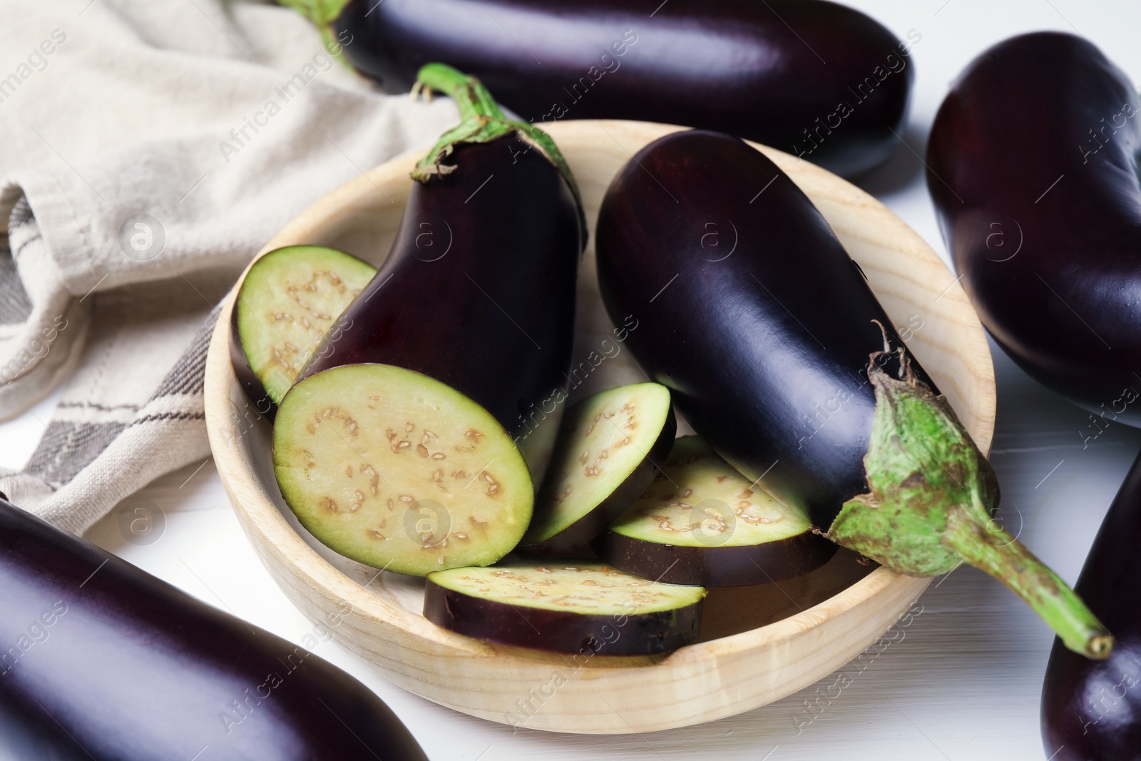 Photo of Whole and cut eggplants on white table, closeup