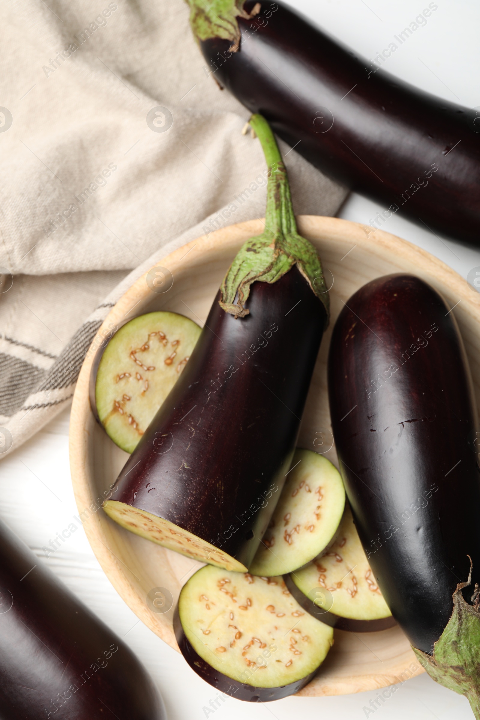 Photo of Whole and cut eggplants on white table, flat lay