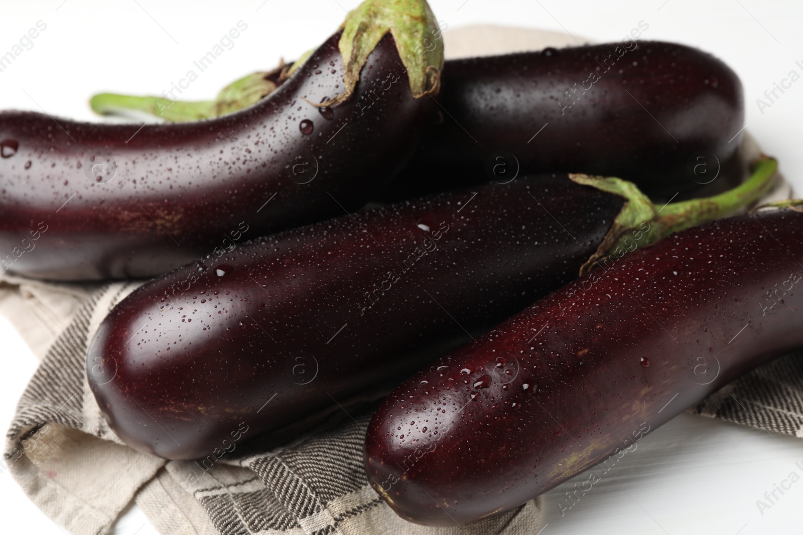 Photo of Many wet ripe eggplants on white table, closeup
