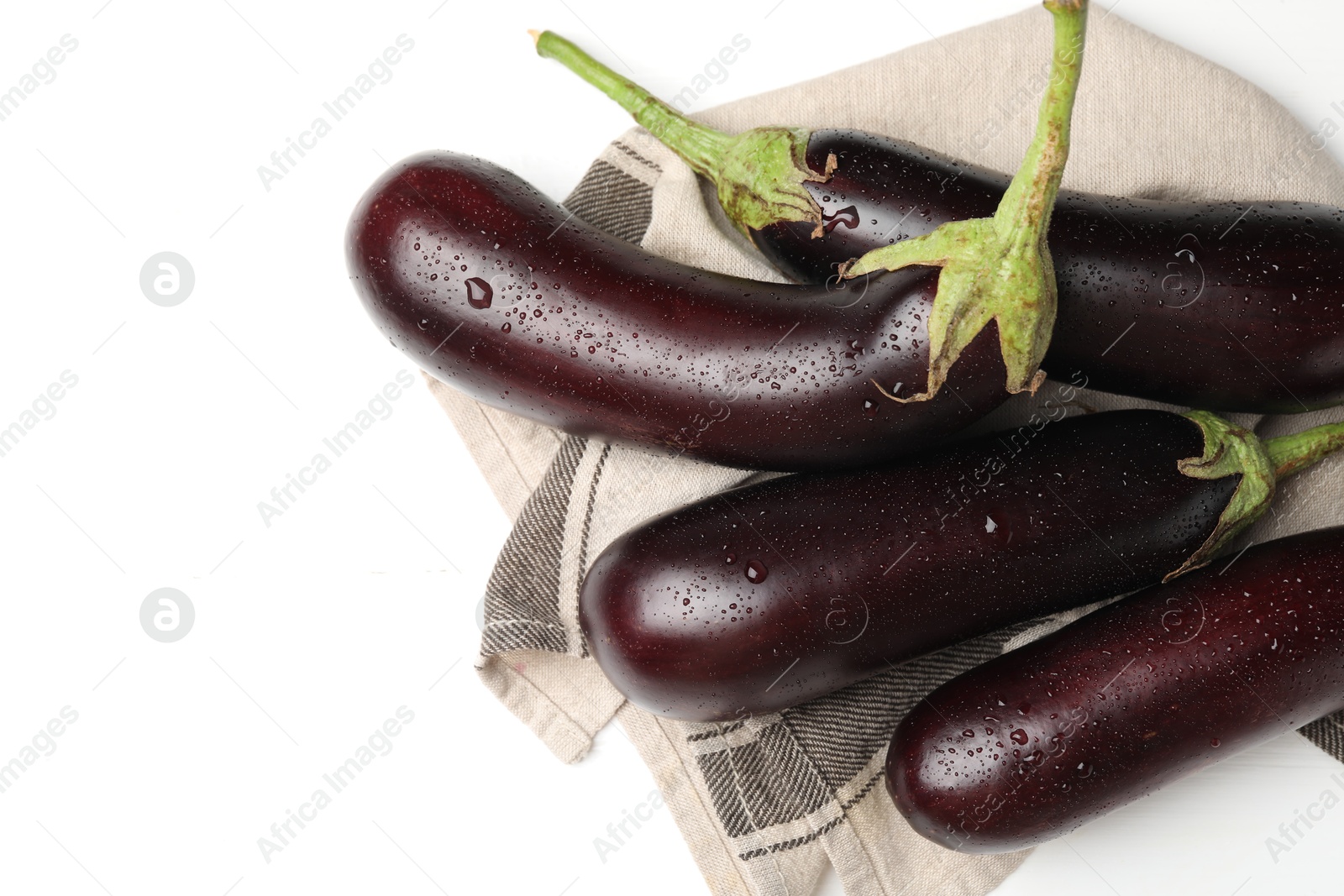 Photo of Many wet ripe eggplants and towel on white table, flat lay