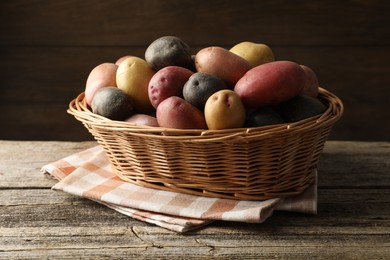 Photo of Different types of potatoes in wicker basket on wooden table