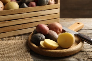 Photo of Different types of potatoes and knife on wooden table, closeup