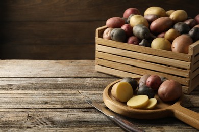 Photo of Different types of potatoes and knife on wooden table, closeup. Space for text