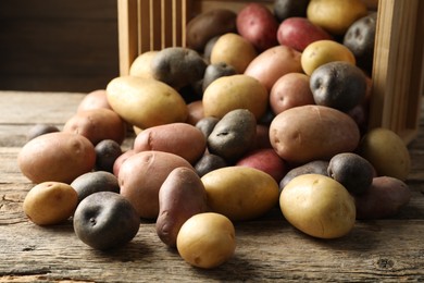 Photo of Different types of potatoes on wooden table, closeup