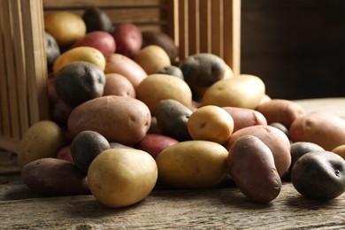 Photo of Different types of potatoes on wooden table, closeup
