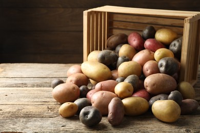 Photo of Different types of potatoes on wooden table, closeup. Space for text