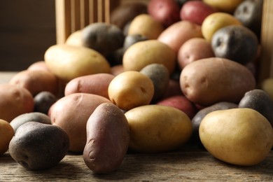 Photo of Different types of potatoes on wooden table, closeup