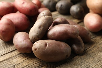 Photo of Different types of potatoes on wooden table, closeup