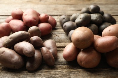 Photo of Different types of potatoes on wooden table, closeup