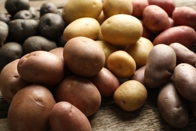 Photo of Different types of potatoes on wooden table, closeup
