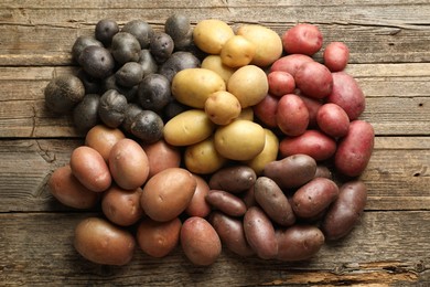 Photo of Different types of potatoes on wooden table, flat lay