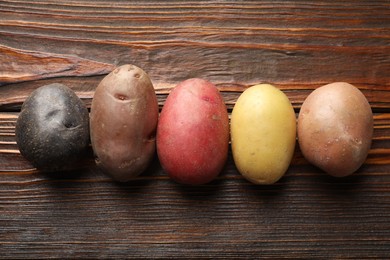 Photo of Different types of potatoes on wooden table, flat lay