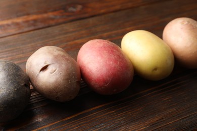 Photo of Different types of potatoes on wooden table, closeup