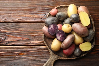 Photo of Different types of potatoes on wooden table, top view. Space for text