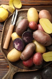Photo of Different types of potatoes and peeler on wooden table, top view