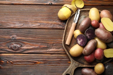 Photo of Different types of potatoes and peeler on wooden table, top view. Space for text