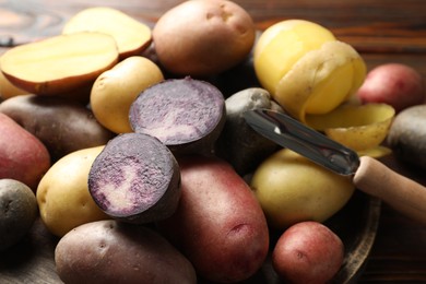 Photo of Different types of potatoes and peeler on table, closeup