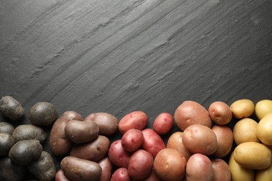 Photo of Different types of potatoes on black table, flat lay. Space for text
