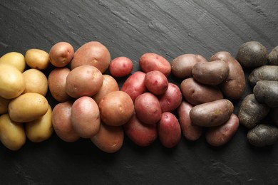 Photo of Different types of potatoes on black table, flat lay