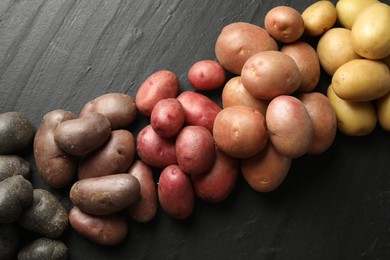 Photo of Different types of potatoes on black table, flat lay